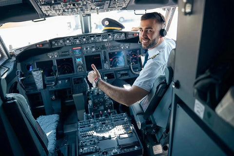 An airline pilot giving a thumbs up in the cockpit of a jet