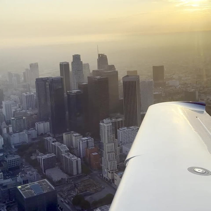 The Downtown Los Angeles skyscrapers seen over the wing of a small airplane circling the towers on a discovery flight