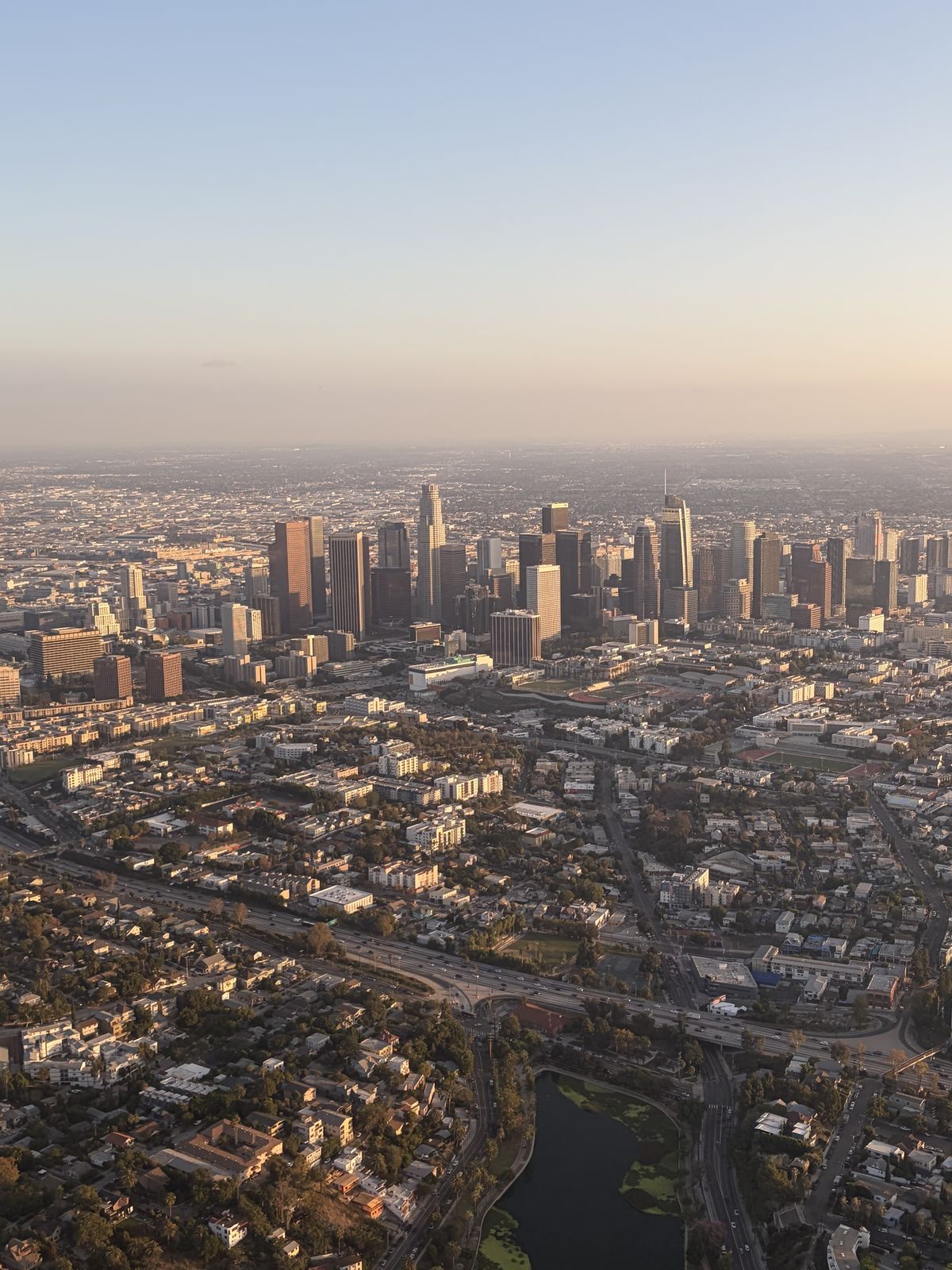 The Downtown Los Angeles skyline at golden hour, seen from a small airplane above Echo Park Lake and the 101 freeway on a discovery flight from Van Nuys