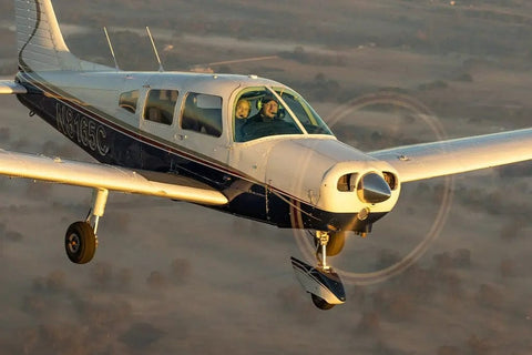 A Piper Archer trainer in flight in warm evening light